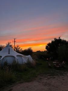 a yurt with a sunset in the background at Moat Island Glamping in Norwich