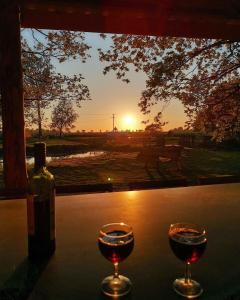 dos copas de vino sentadas en una mesa con la puesta de sol en Moat Island Glamping, en Norwich