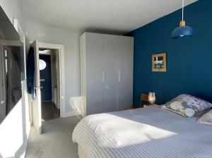 um quarto com uma cama e uma parede azul em Bright flat in Stoke Newington em Londres