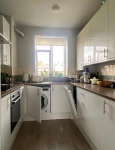a large kitchen with white cabinets and a window at Bright flat in Stoke Newington in London