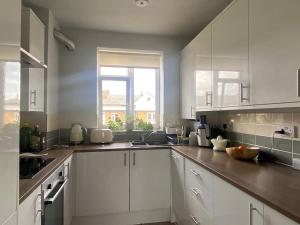 uma grande cozinha com armários brancos e uma janela em Bright flat in Stoke Newington em Londres