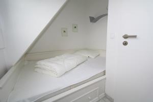 uma cama com lençóis brancos e almofadas em Spieker em Wenningstedt