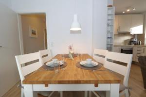 a wooden table with white chairs and a dining room at Entennest am Dorfteich in Wenningstedt
