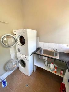 a small kitchen with a washing machine and a sink at Beach Cottage in Bellerive
