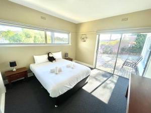 1 dormitorio con 1 cama blanca grande y balcón en Beach Cottage, en Bellerive