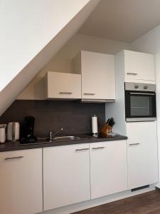 uma cozinha com armários brancos e um lavatório em Hotel Schöne Aussicht em Wilhelmshaven
