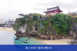 a building on top of a cliff next to the beach at Hotel SERA LUNA -ホテル セラルナ- in Naha