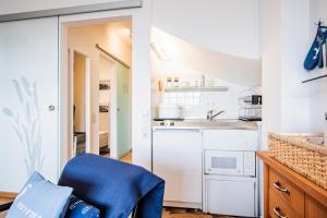 uma cozinha branca com um lavatório e uma cadeira azul em Atlantik 23 -Standnahe Ferienwohnung em Wenningstedt