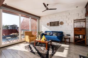 a living room with a blue couch and a table at SaffronStays Calvin - 3 Bedroom Pool Villa In Lonavala in Lonavala