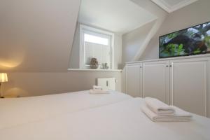 1 dormitorio blanco con 1 cama grande y TV en Kiebitz-Nordseebrise - Wenningstedt, en Wenningstedt