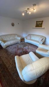 - un salon avec des canapés en cuir blanc et une table dans l'établissement Am Sonnenberg, à Reichelsheim
