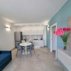 a kitchen and living room with a table and chairs at Brezza Salentina Aparthotel in Torre San Giovanni Ugento