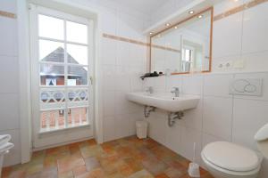 een badkamer met een wastafel, een toilet en een raam bij Thomas Mann /Landhaus Friedrichshain in Wenningstedt