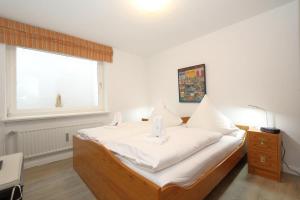 1 dormitorio con 1 cama con sábanas blancas y ventana en Sommer Munkmarsch, en Munkmarsch