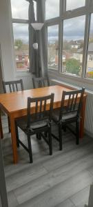 a dining room table with chairs and a large window at Serviced Accommodation in London in Croydon