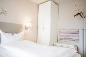 Dormitorio blanco con cama y armario en Spalthoff 18, en Westerland