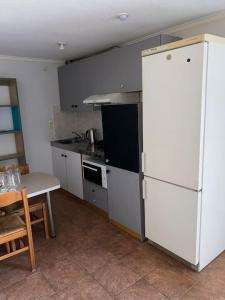 a kitchen with a white refrigerator and a table at Μεζονέτα Χιόνα in Chios