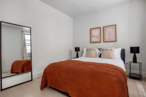 a bedroom with a large bed with an orange blanket at Blueground Chelsea elevator wd nr 8th Ave NYC-1448 in New York