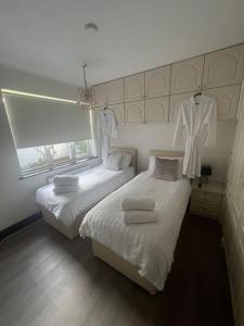 two beds in a bedroom with white sheets and towels at Entire Property & Luxury Pool, Wi-Fi & Parking in Southend-on-Sea