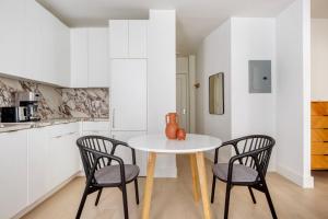 a white kitchen with a table and two chairs at Blueground Chelsea elevator wd nr 8th Ave NYC-1449 in New York