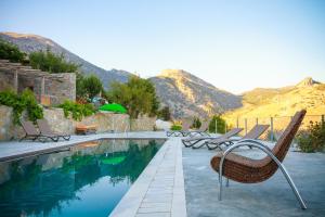 a pool with chairs and mountains in the background at Pezoulia in Selakano