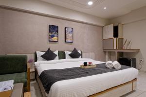 a bedroom with a large bed and a couch at Exora Inn in Ahmedabad