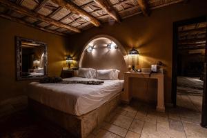 a bedroom with a bed with an arched window and a mirror at Kasbah Hotel Xaluca Arfoud in Erfoud