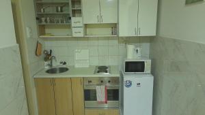una piccola cucina con armadietti bianchi e frigorifero bianco di Vracar Krunska Jamiva a Belgrado