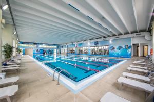 a large swimming pool in a building with white chairs at Hotel Belvedere in Cluj-Napoca