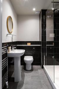 bagno con lavandino, servizi igienici e specchio di The Bridge Hotel a Chertsey