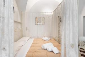 Cette chambre blanche comprend 2 lits et des rideaux. dans l'établissement House&Villas - La Casa di Benso, à Noto