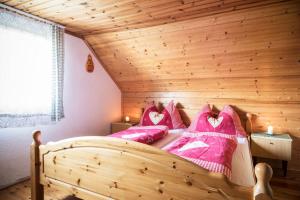 1 dormitorio con cama de madera y almohadas rosas en Brandner Almhütte en Schoberegg