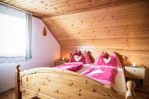 a bedroom with a wooden bed with pink pillows at Brandner Almhütte in Schoberegg