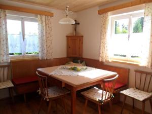 una mesa y sillas en una habitación con ventanas en Brandner Almhütte en Schoberegg