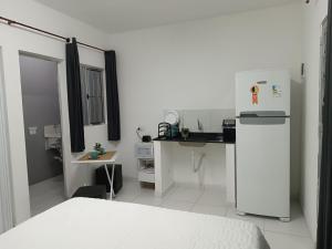 a small white kitchen with a refrigerator and a table at Inovally in Guarulhos