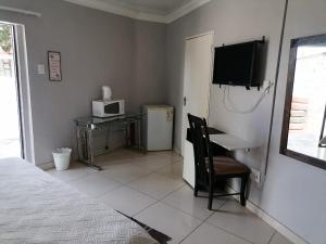 a bedroom with a bed and a desk and a microwave at Eeufees Guesthouse in Bloemfontein