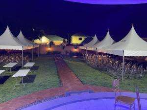 JLK Guest House & Events Centre في Koforidua: مجموعة من الخيام مع طاولات وكراسي تحتها
