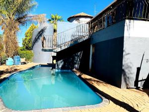 a swimming pool with a balcony on top of a house at Eeufees Guesthouse in Bloemfontein