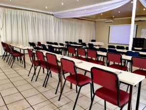 einen Konferenzraum mit Tischen, Stühlen und einem Bildschirm in der Unterkunft Eeufees Guesthouse in Bloemfontein