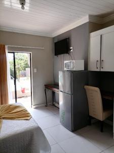 a kitchen with a refrigerator and a table in a room at Eeufees Guesthouse in Bloemfontein