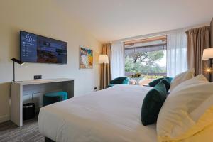 ein Hotelzimmer mit einem großen Bett und einem Fenster in der Unterkunft Golf Hôtel de Valescure & Spa NUXE in Saint-Raphaël