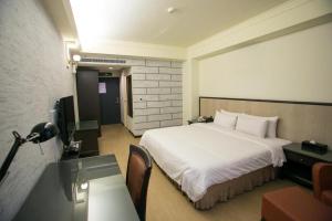 ein Hotelzimmer mit einem großen Bett und einem Schreibtisch in der Unterkunft Huang Shin Business Hotel-Shang An in Taichung