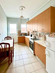 een keuken met houten kasten, een tafel en een witte koelkast bij Bella Vista Apartment in Chios