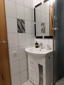 Baño blanco con lavabo y espejo en Apartments Anna, en Leópolis