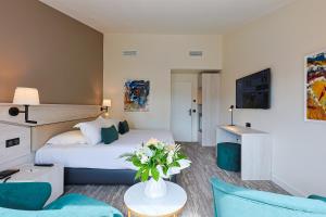 um quarto de hotel com uma cama e uma mesa com flores em Golf Hôtel de Valescure & Spa NUXE em Saint-Raphaël