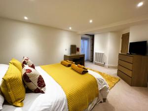 a bedroom with a large bed with yellow blankets and pillows at 2 Shanklin Manor - Ground Floor apartment overlooking Park in Shanklin Old Village in Shanklin