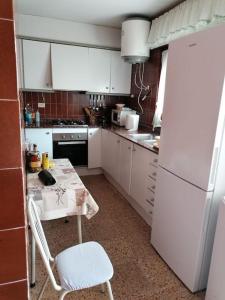 a kitchen with a table and a white refrigerator at Casa Gares in Peñíscola