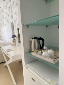 a cupboard with a tea kettle and dishes on it at Mare Monte Small Boutique Hotel in Chrysi Ammoudia