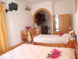 a bedroom with two beds and a table with flowers at Studios Irene in Skala