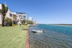 a boat sitting in the water next to a building at River Front Escape, Walk to Ocean St & Shops in Maroochydore